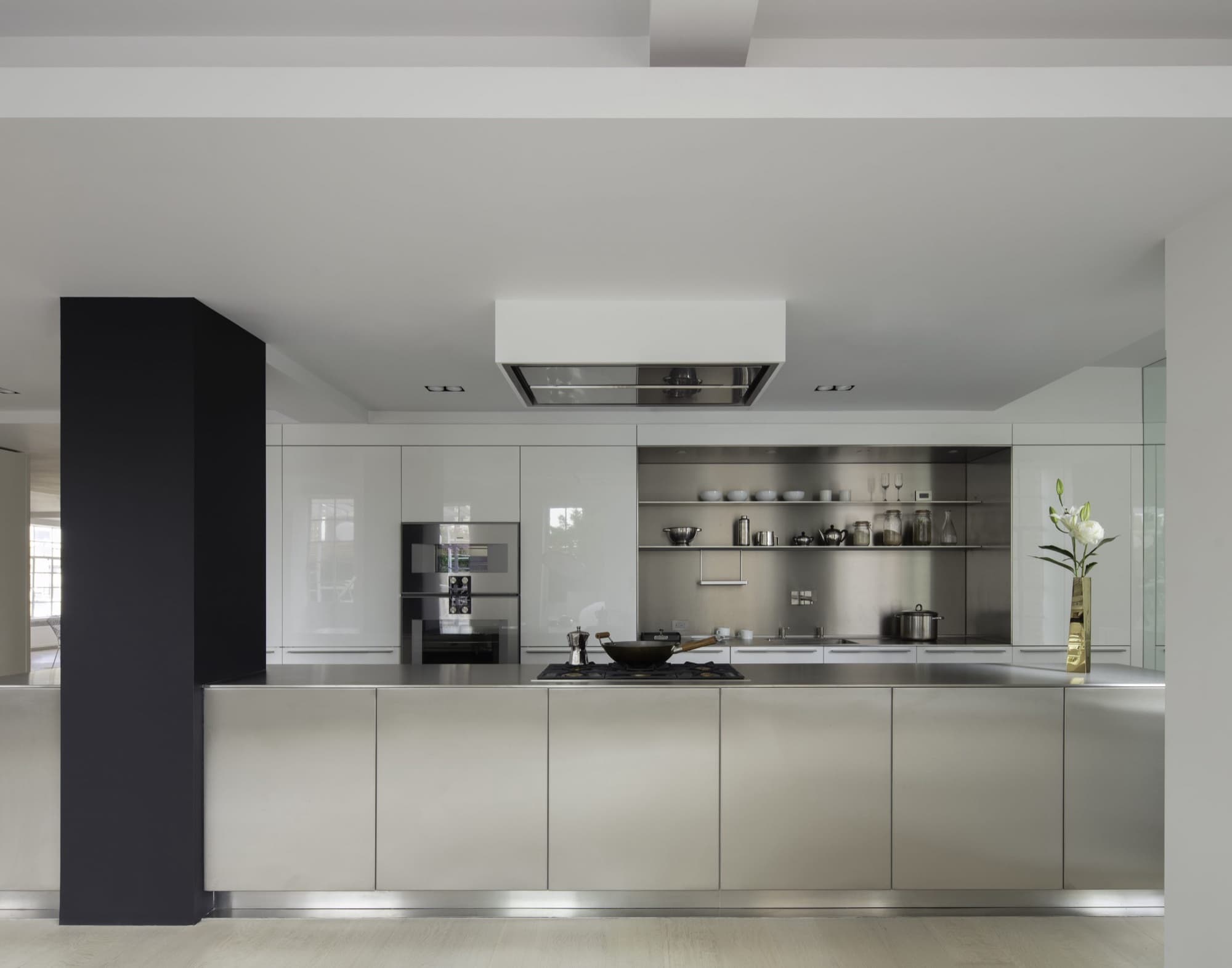 Bulthaup b3 kitchen — stainless-steel island and worktop, white high-gloss cabinetry, stainless open shelving, ceiling-mounted extractor